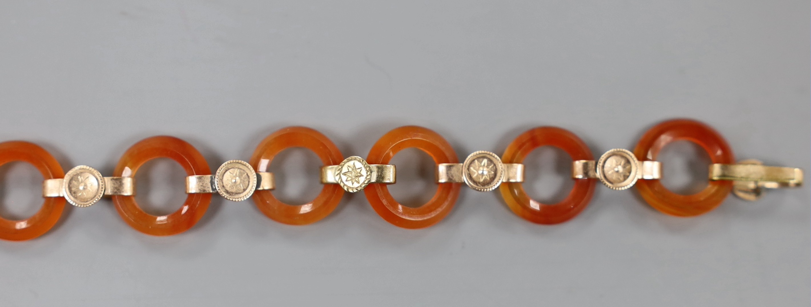 Part of an early 20th century yellow metal and carnelian disc link set bracelet, 14.6cm, gross weight 7.3 grams.